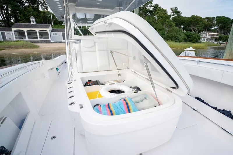 Slide: The Image of 2023 Invincible 39 Open Fisherman boat with open storage compartment, docked near a scenic shoreline. - 19