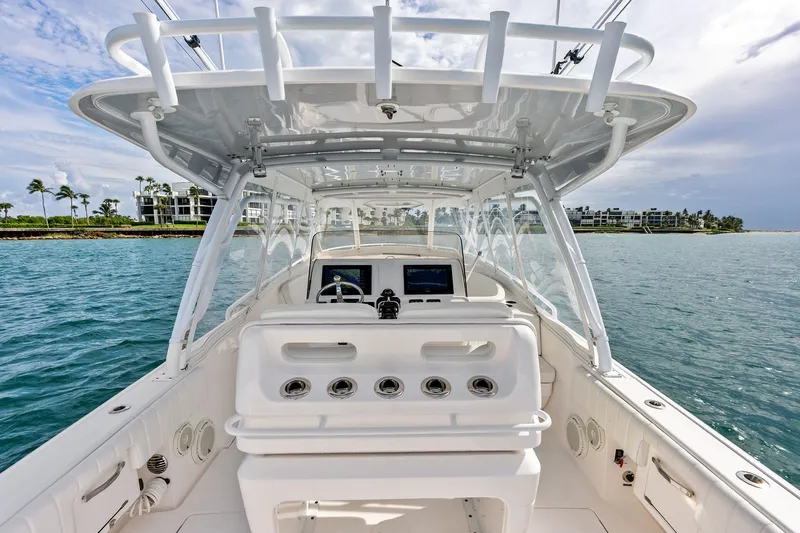 Slide: The Image of 2019 Intrepid 400 Cuddy boat interior with helm, ocean view, and coastal background. - 18