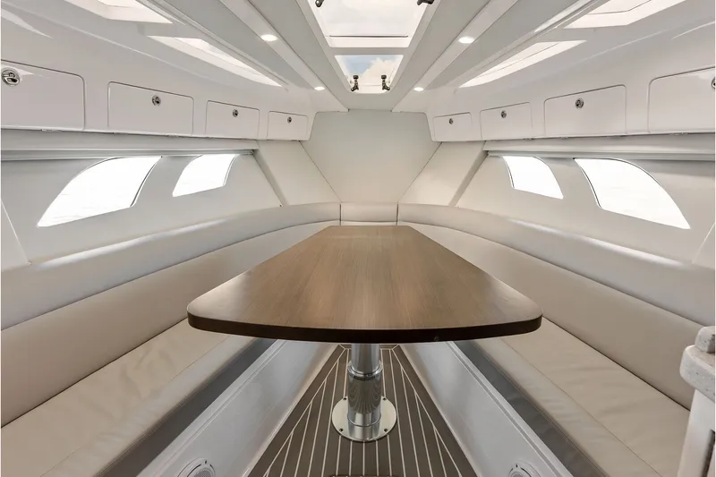 Slide: The Image of 2019 Intrepid 400 Cuddy interior with sleek table, cushioned seating, and overhead storage. - 46