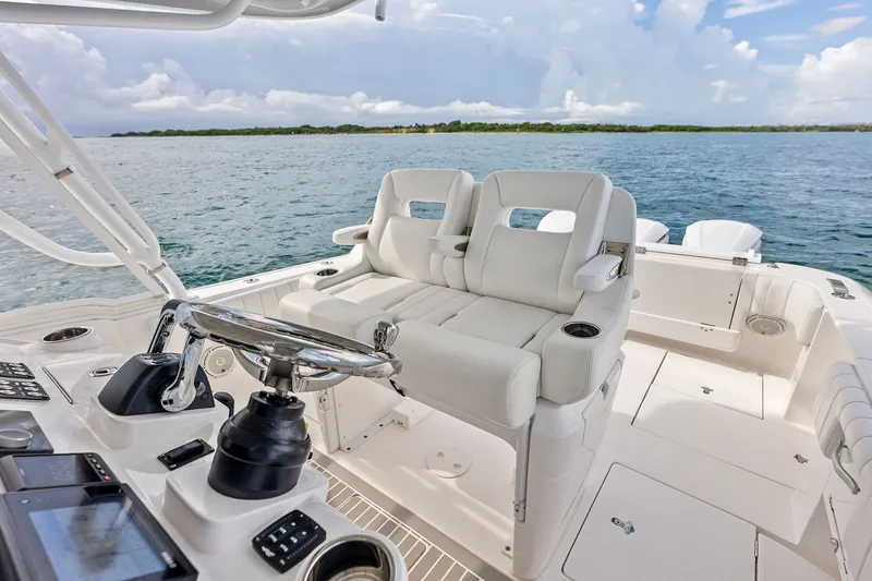Slide: The Image of 2019 Intrepid 400 Cuddy boat interior with helm and seating, on calm water. - 15