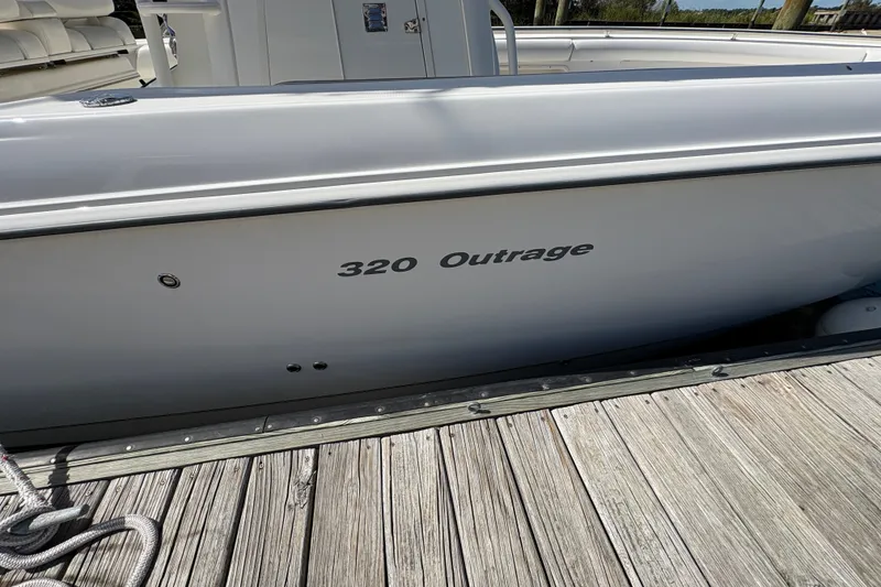 Slide: The Image of 2011 Boston Whaler 320 Outrage boat docked, showcasing sleek design and branding. - 52