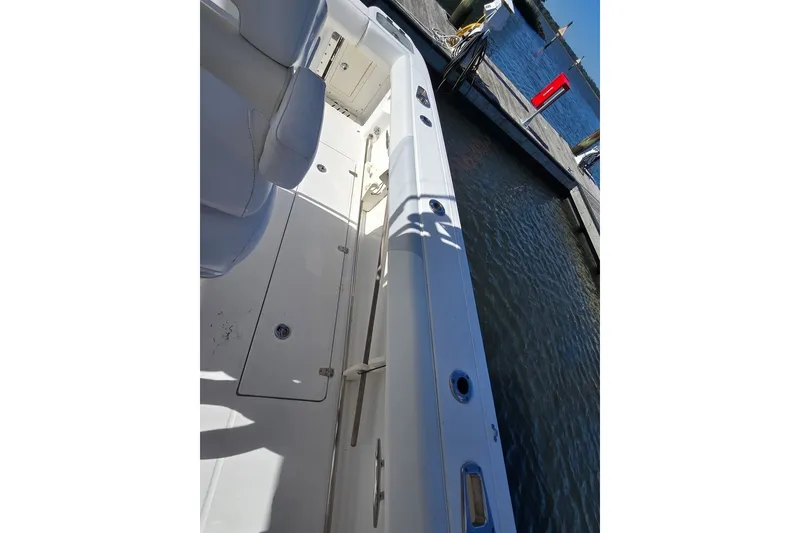 Slide: The Image of 2011 Boston Whaler 320 Outrage docked, showcasing sleek white deck and seating. - 34
