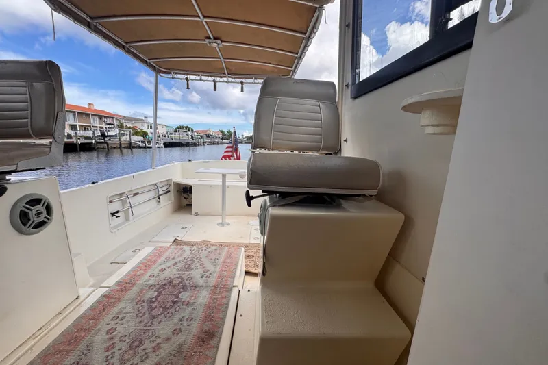 Slide: The Image of Interior view of 2005 Atlas Boat Works Acadia 25, featuring seating and waterfront backdrop. - 41