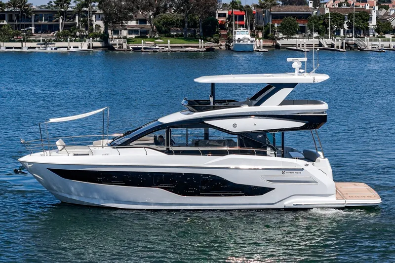 Slide: The Image of 2027 Cruisers Yachts 50 Fly luxury yacht cruising on a serene waterfront. - 9