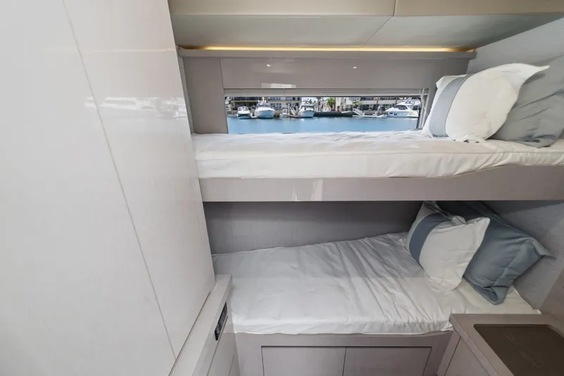 Slide: The Image of Interior of 2027 Cruisers Yachts 50 Fly, featuring cozy bunk beds with marina view. - 87