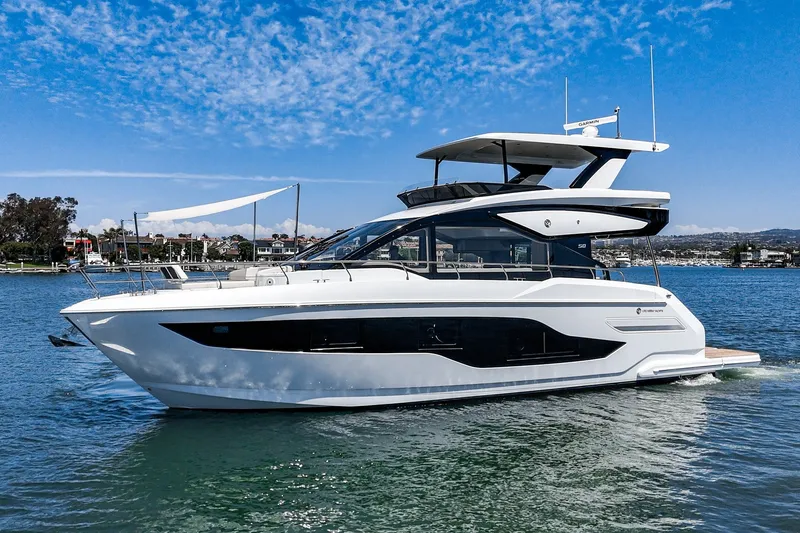 Slide: The Image of 2027 Cruisers Yachts 50 Fly luxury yacht on serene water, clear blue sky backdrop. - 16