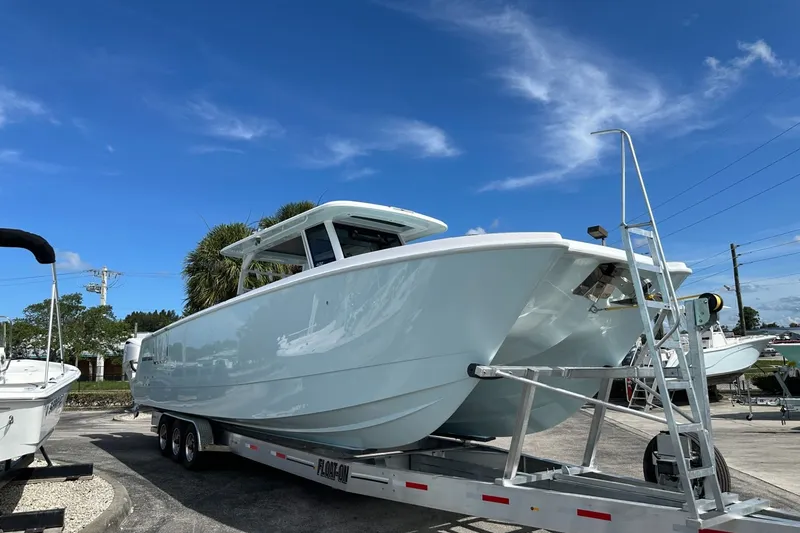 Slide: The Image of 2025 Twin Vee 400 GFX2 CC boat on trailer under clear blue sky. - 4