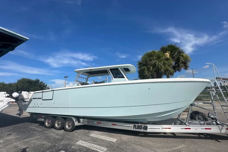 Slide: The Image of 2025 Twin Vee 400 GFX2 CC boat on trailer under clear blue sky. - 3