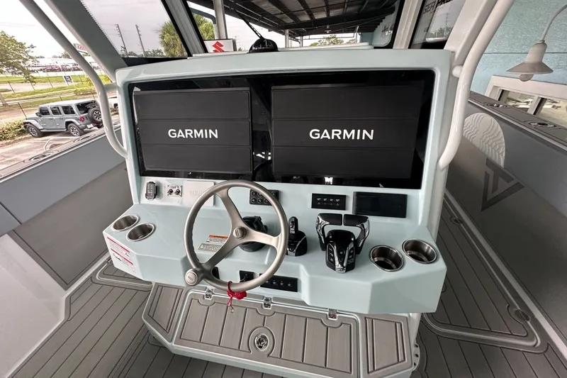 Slide: The Image of 2025 Twin Vee 400 GFX2 CC boat dashboard with Garmin displays and steering wheel. - 8