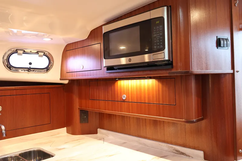 Slide: The Image of 2023 Pursuit OS 385 Offshore yacht interior with microwave and wooden cabinetry. - 39