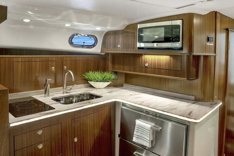 Slide: The Image of Manufacturer Provided Image: Modern kitchen in 2023 Pursuit OS 385 Offshore boat with wood cabinetry, stainless steel appliances, and marble countertop. - 6