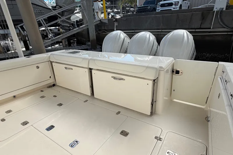 Slide: The Image of 2023 Pursuit OS 385 Offshore boat deck with storage compartments and triple outboard engines. - 14