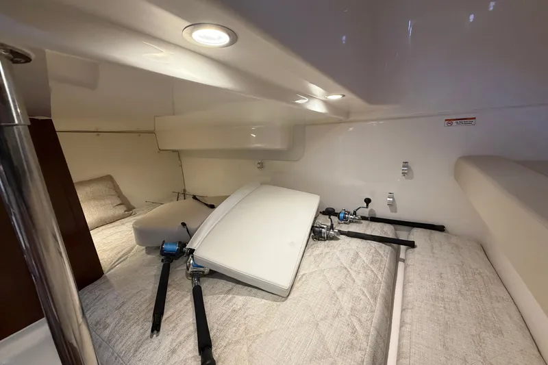 Slide: The Image of 2023 Pursuit OS 385 Offshore cabin interior with fishing rods and cozy bedding. - 50