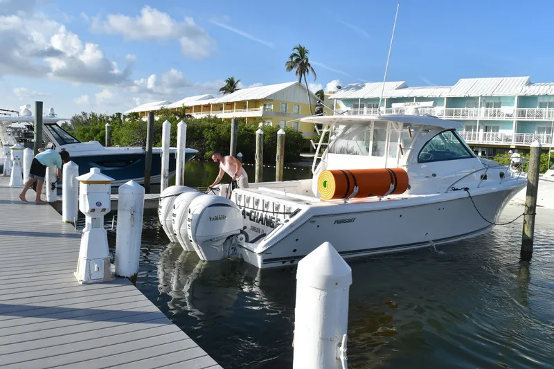 Slide: The Image of 2023 Pursuit OS 385 Offshore boat docked at marina with people nearby. - 1