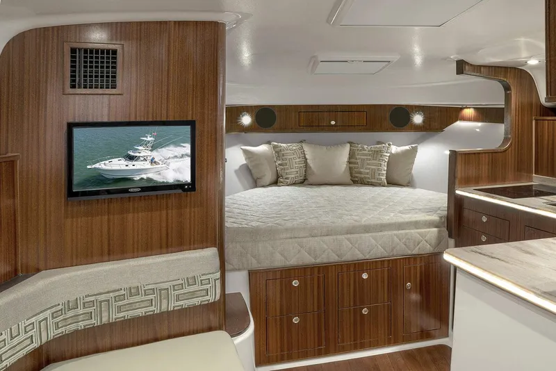 Slide: The Image of Manufacturer Provided Image: Luxurious cabin interior of the 2023 Pursuit OS 385 Offshore boat with a cozy bed and TV. - 7
