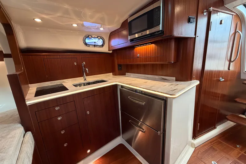 Slide: The Image of Luxurious 2023 Pursuit OS 385 Offshore yacht kitchen with wood cabinetry and modern appliances. - 36