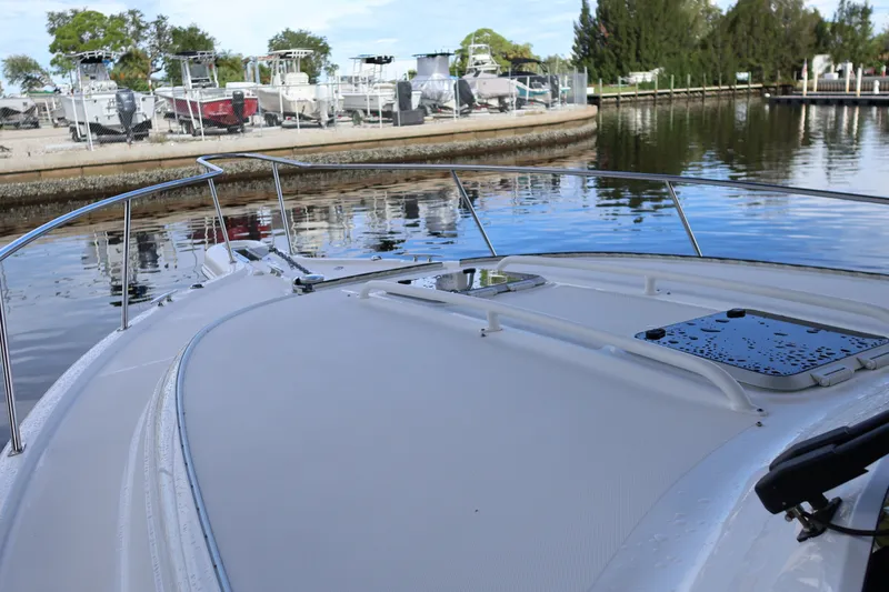 Slide: The Image of 2023 Pursuit OS 385 Offshore boat docked near marina, calm water reflection. - 55