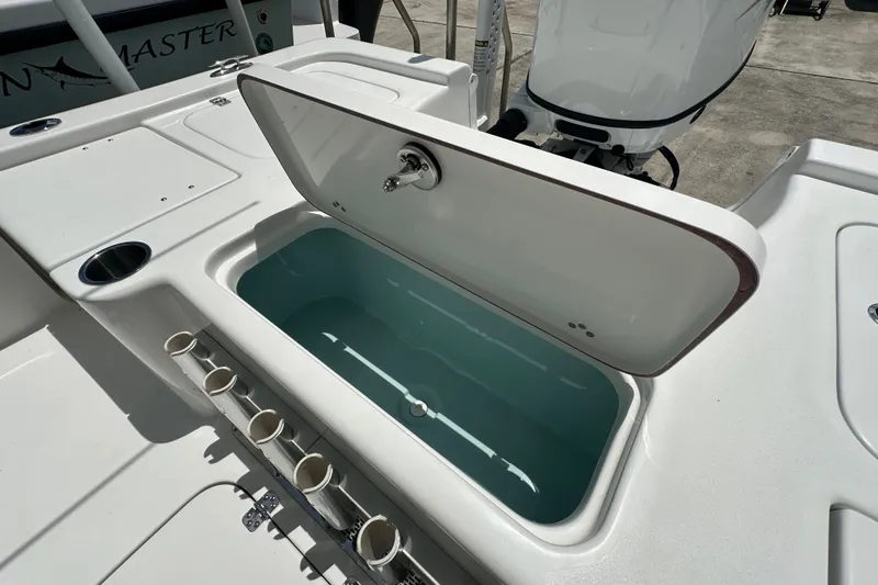 Slide: The Image of Open storage compartment on 2026 Sea Pro 230 Bay boat, featuring rod holders and cup holder. - 17