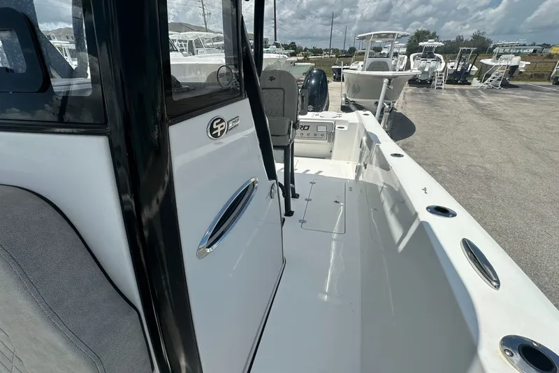 Slide: The Image of 2024 Sea Pro 262 Center Console boat, sleek design, parked outdoors under cloudy sky. - 13