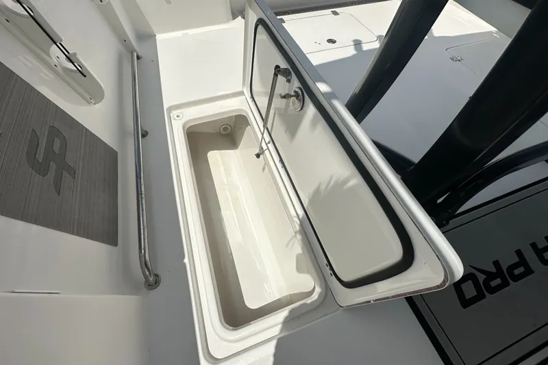 Slide: The Image of 2024 Sea Pro 262 Center Console boat storage compartment with open lid and stainless steel railing. - 16