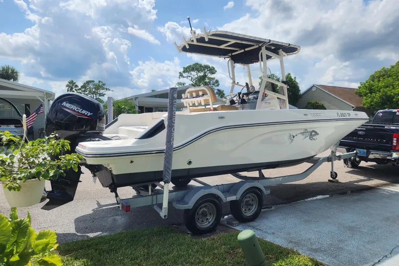 Slide: The Image of 2024 Bayliner Trophy T22CC boat on trailer, parked outdoors under a cloudy sky. - 1
