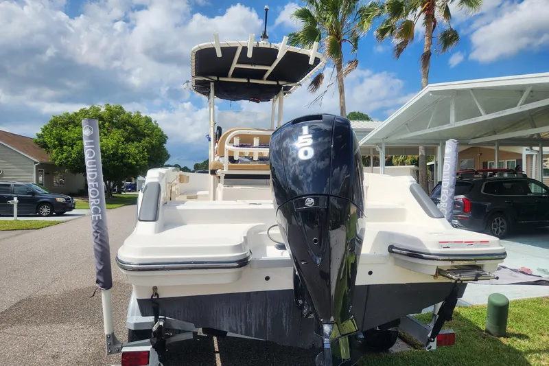 Slide: The Image of 2024 Bayliner Trophy T22CC boat with 150 HP engine, parked outdoors under a sunny sky. - 2