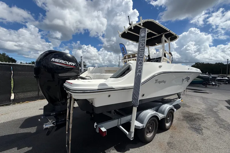 Slide: The Image of 2024 Bayliner Trophy T22CC boat with Mercury engine on trailer under cloudy sky. - 2