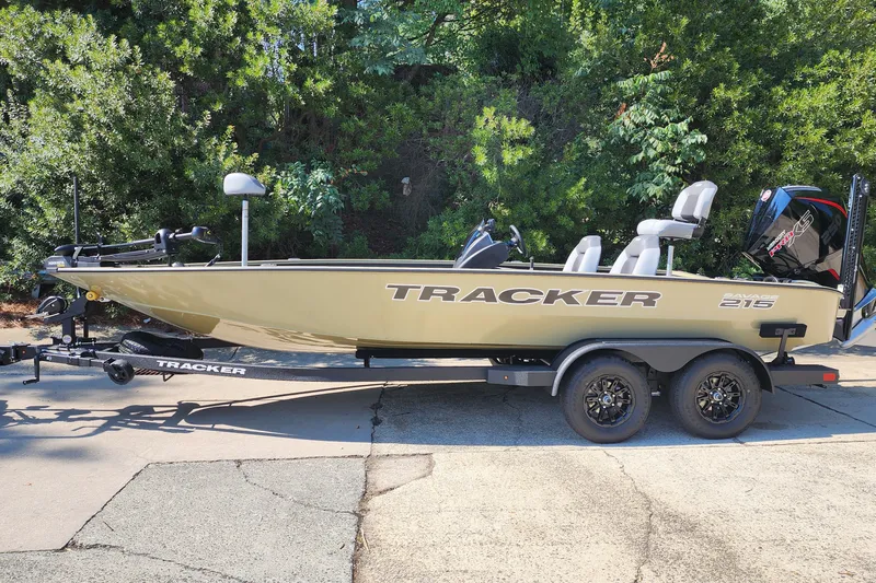 The Image of 2027 Tracker Savage 215 boat on trailer, parked outdoors with lush greenery background. - 1