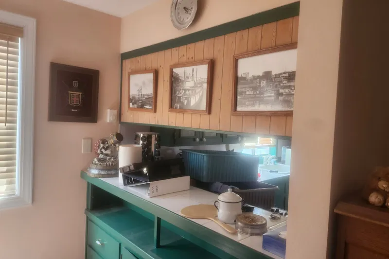 Slide: The Image of Cozy 1973 custom boat house kitchen with vintage decor and framed nautical photos. - 21