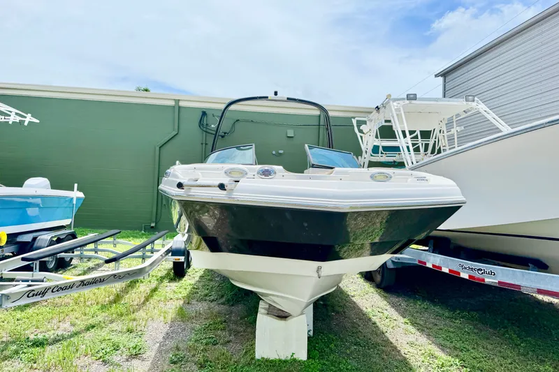 Slide: The Image of 2019 NauticStar 243 DC boat on display, parked outdoors with trailers nearby. - 2