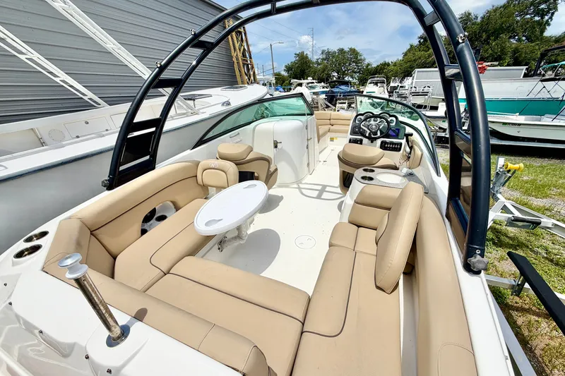 Slide: The Image of 2019 NauticStar 243 DC boat interior with beige seating and modern dashboard. - 7