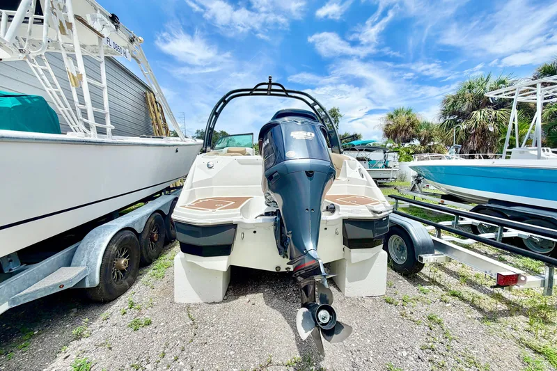 Slide: The Image of 2019 NauticStar 243 DC boat with outboard motor, parked on a trailer under a clear sky. - 5