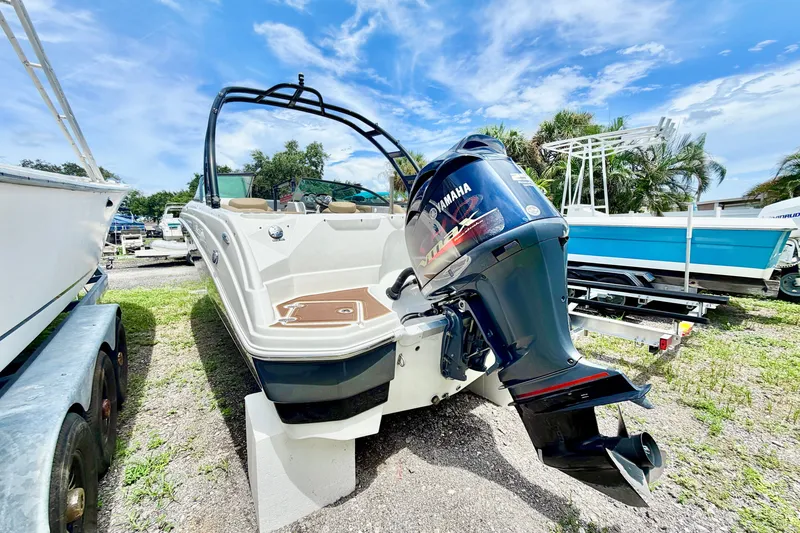 Slide: The Image of 2019 NauticStar 243 DC boat with Yamaha outboard motor, parked outdoors under a blue sky. - 6