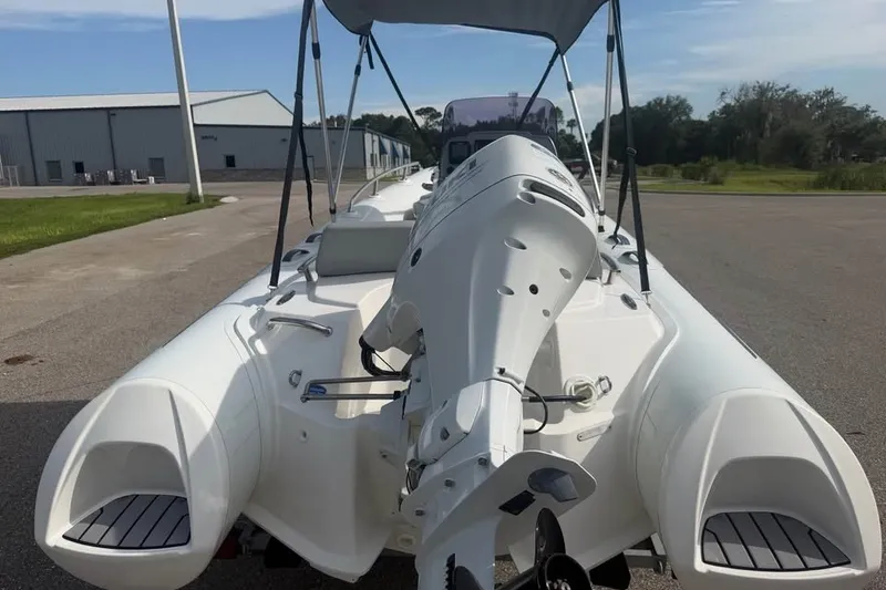 Slide: The Image of 2023 Grand G420 boat with outboard motor and canopy, parked on pavement near industrial buildings. - 5