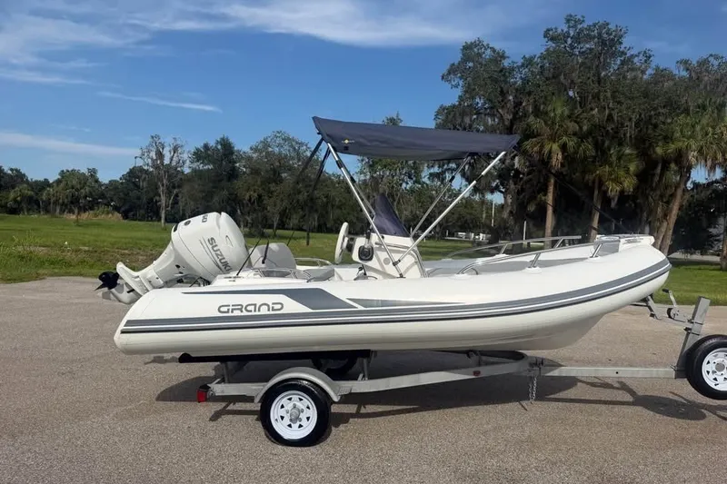 The Image of 2023 Grand G420 boat on trailer with Suzuki outboard motor, parked outdoors. - 1