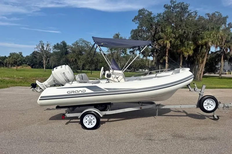 Slide: The Image of 2023 Grand G420 boat on trailer with Suzuki outboard motor, parked outdoors. - 3