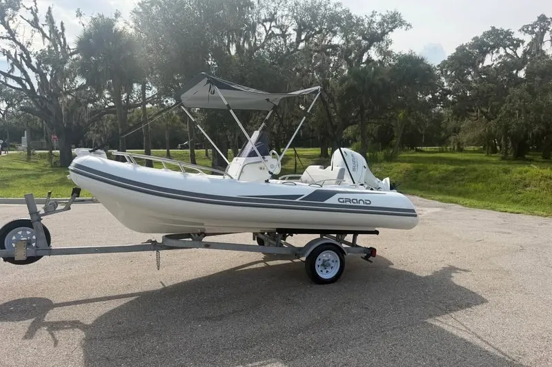 Slide: The Image of 2023 Grand G420 inflatable boat on trailer, parked outdoors with trees in background. - 9