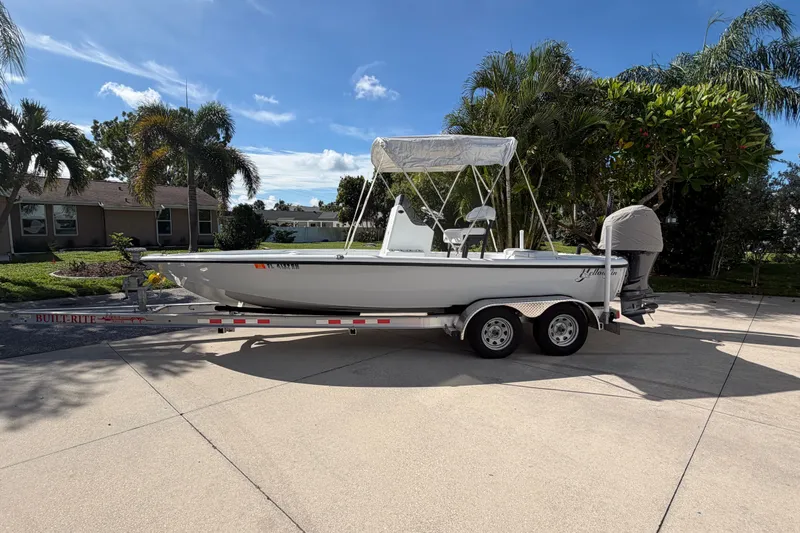 Slide: The Image of 2018 Yellowfin 21 Bay boat on trailer, parked in sunny driveway with palm trees. - 6