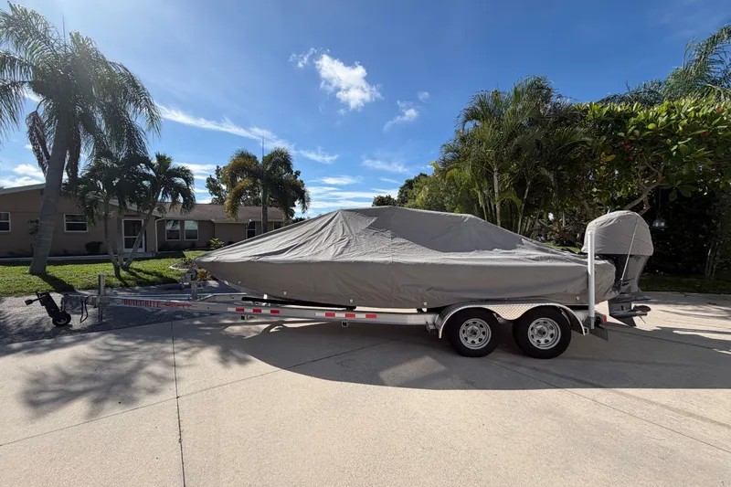 Slide: The Image of 2018 Yellowfin 21 Bay boat covered on trailer, surrounded by palm trees. - 51