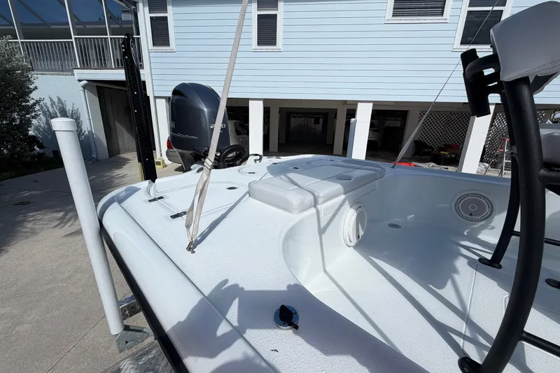 Slide: The Image of 2018 Yellowfin 21 Bay boat with motor, parked near a light blue house. - 16