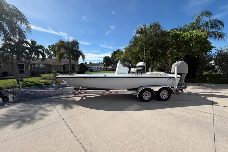 The Image of 2018 Yellowfin 21 Bay boat on trailer, parked in a driveway with palm trees. - 0