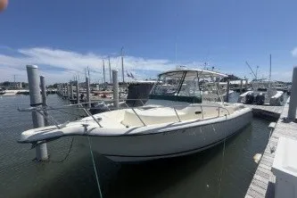 The Image of 2000 Pursuit 2870 Offshore Center Console boat docked at a marina under a clear blue sky. - 0