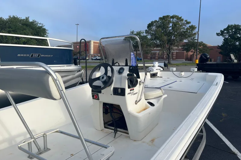 Slide: The Image of 2021 Mako Pro Skiff 17 CC boat with center console and steering wheel in a parking lot. - 7