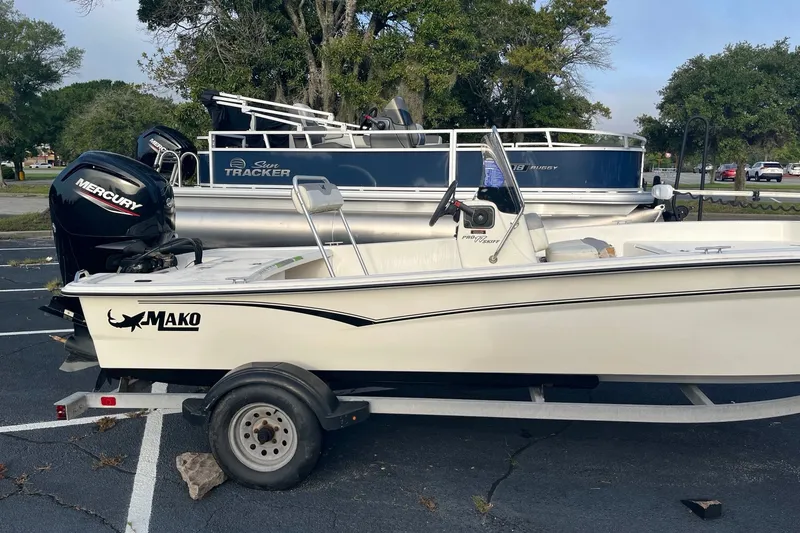 Slide: The Image of 2021 Mako Pro Skiff 17 CC boat on trailer, parked outdoors with trees in background. - 8