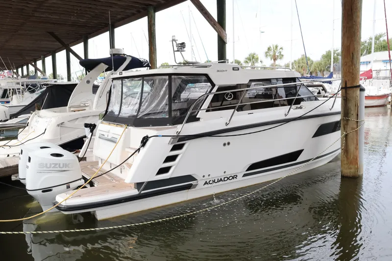 Slide: The Image of 2024 Aquador 300 HT boat docked with Suzuki outboard motor. - 58