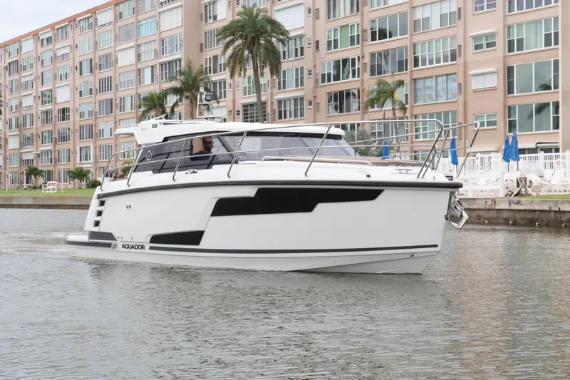 Slide: The Image of 2024 Aquador 300 HT boat cruising near waterfront buildings. - 57
