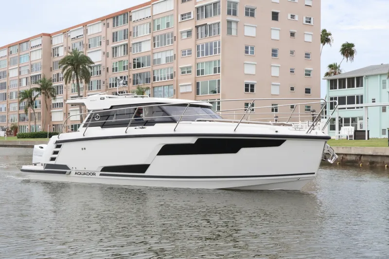 Slide: The Image of 2024 Aquador 300 HT boat cruising near waterfront buildings. - 4