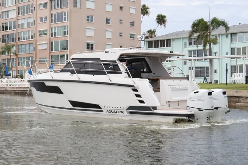 Slide: The Image of 2024 Aquador 300 HT boat cruising near waterfront buildings. - 9