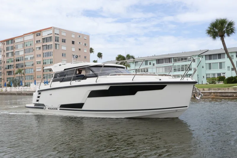 Slide: The Image of 2024 Aquador 300 HT boat cruising near waterfront buildings and palm trees. - 3