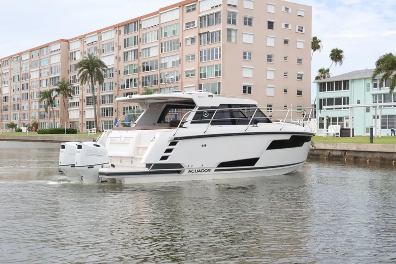 Slide: The Image of 2024 Aquador 300 HT boat cruising near waterfront buildings. - 6
